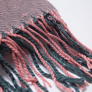 Close-up of pink and green twill knit scarf with twisted fringe details and texture