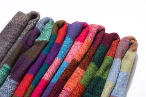 Close-up of stacked colorful striped knit scarves with detailed wool textures