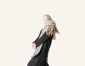 Detail of grey wool scarf with fringe styled on a black coat for autumn and winter look