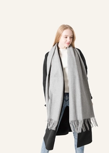 Light gray wool scarf with fringe detail shown on model wearing black coat