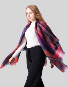 Detail of soft red and purple plaid shawl scarf with classic tartan pattern and fringe