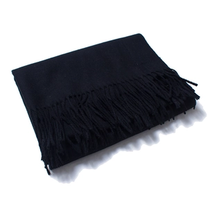 Detailed close-up of a folded black wool scarf featuring dense fringe trim on the edges