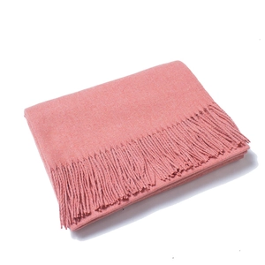 Close-up of coral pink wool scarf featuring long fringes and soft thick texture