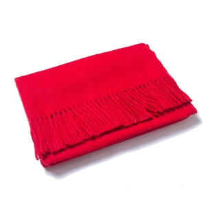 Detailed view of red wool scarf with fringe edge, showing soft texture and thickness