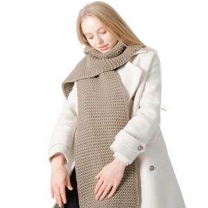 Thick beige chunky knit scarf for winter shown on a model with a white wool coat