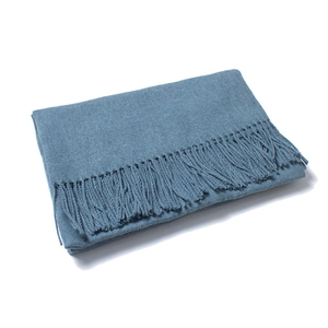 Detailed close-up of blue scarf showing soft knit texture and fringe tassels on white backdrop