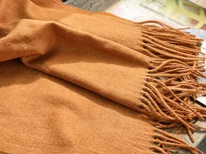 Primer plano de bufanda de lana color caramelo con textura suave y detalle flecos