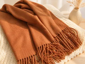 Detalle de bufanda de lana color caramelo con textura suave y flecos largos decorativos