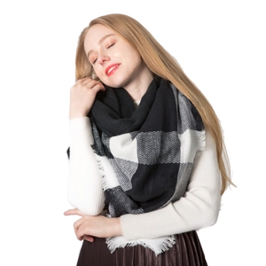 Classic black and white oversized checkered scarf with fringe worn by a smiling model