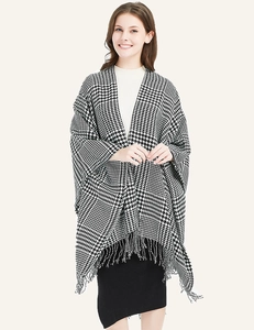 Detail of soft houndstooth poncho featuring fine tassel hem and classic knit texture
