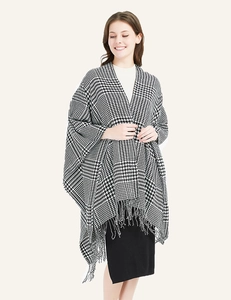 Detailed view of black and white houndstooth poncho featuring soft fringe edges and knit texture