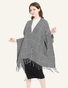 Detailed close-up of houndstooth knit poncho featuring elegant tassel trim and premium fabric