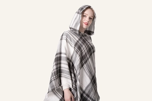 Vista dettagliata di un poncho con cappuccio a quadri neri e grigi con frange morbide