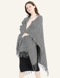 Detailed view of black and white houndstooth knit shawl with elegant tassel fringe texture
