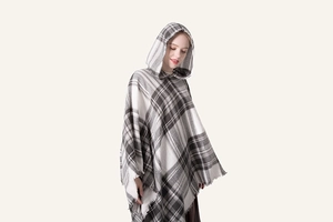 Dettaglio della trama a maglia scozzese spessa e frange sul poncho invernale con cappuccio