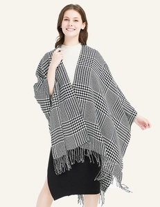 Detailed view of the houndstooth poncho featuring soft tassels and classic black and white weave