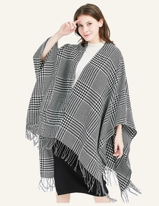 Detailed view of black and white houndstooth poncho with fringe edges and knit texture