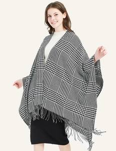 Detail of classic black and white houndstooth poncho featuring long fringe tassels on the hem