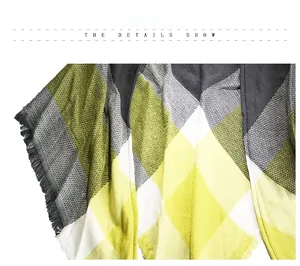 Detail view of plaid cashmere shawl with olive green and yellow diamond patterns and fringe