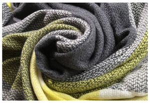 Macro view of soft faux cashmere knit fabric showing yellow and grey plaid pattern