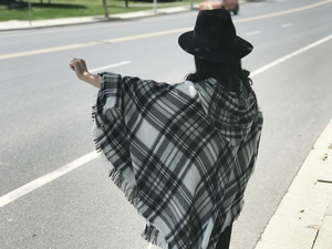 Dettaglio di un poncho a quadri bianco e nero con bordi sfrangiati per l'inverno