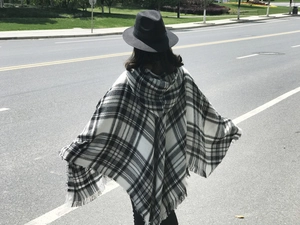Dettaglio di un poncho con cappuccio a scacchi bianchi e neri con orlo a frange fini