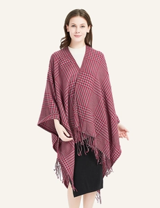 Close-up of houndstooth knit fabric texture and elegant fringe tassels on the poncho