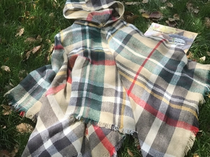 Dettaglio del poncho con cappuccio a quadri multicolore con frange e trama spessa