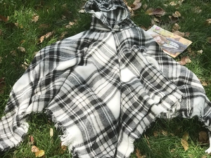 Dettaglio macro del poncho con cappuccio a quadri bianchi e neri e bordi sfrangiati