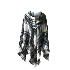 Dettaglio del poncho con cappuccio a quadri bianchi e neri con frange lunghe e tessuto morbido