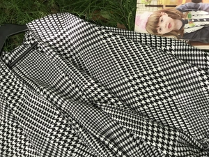 Close-up detail of black and white houndstooth wool shawl with elegant fringe texture
