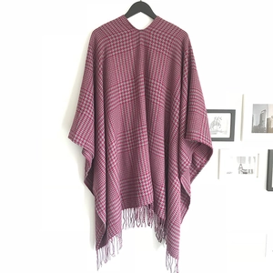 Detailed close-up of red and grey houndstooth shawl with elegant fringe tassel edges