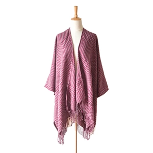 Close-up of red and grey houndstooth poncho shawl with fringe hem on a mannequin