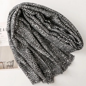 Leopard print cotton linen scarf with frayed edges shown laid flat with a magazine