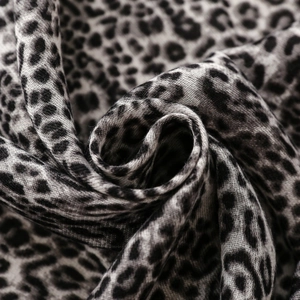 Macro detail of leopard print scarf fabric showing soft weave and fringed edge texture