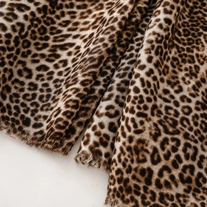 Detail view of leopard print scarf fabric showing soft texture and fringe edges