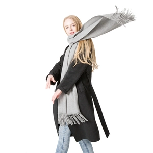 Light gray wool scarf with tassels worn by model against a clean white background
