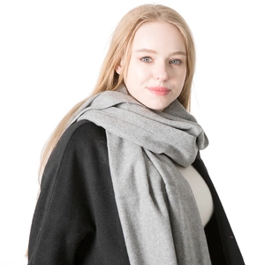 Solid grey wool scarf with fringe for winter worn by a model on a white background