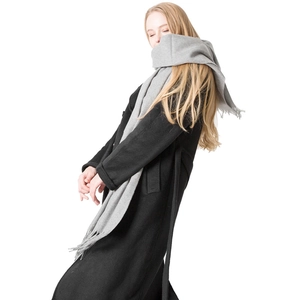 Classic grey wool scarf with fringe detail worn over a black coat on a model