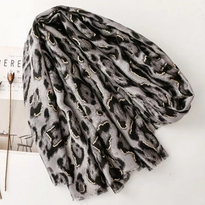 Detail of grey leopard print scarf with gold accents and frayed edges on white background