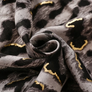 Close-up of leopard print scarf fabric with gold foil accents and soft textured cotton linen