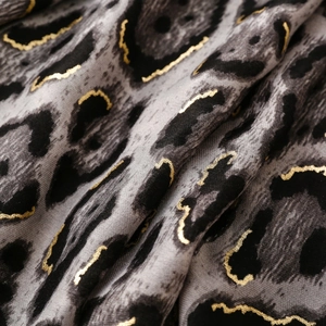 Close-up of soft grey leopard print scarf with golden metallic foil accents and fabric texture