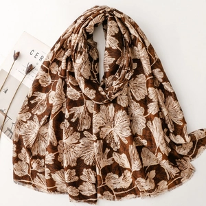 Brown long scarf with beige ginkgo leaf print and frayed edges on white background
