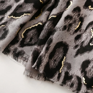 Close-up of leopard print scarf featuring gold foil accents and frayed fringe edges
