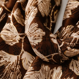 Macro detail of brown cotton linen scarf featuring gold foil gingko leaf print and soft texture