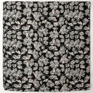 Detailed flat lay of black cotton linen scarf with white ginkgo leaf print and frayed edges