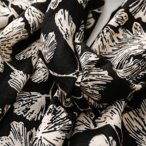 Detailed close-up of cotton linen scarf with black and white print and gold foil leaves