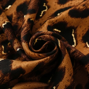 Macro detail of leopard print scarf fabric with gold foil accents and soft textured weave