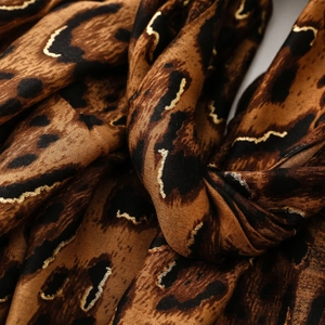 Macro detail of leopard print shawl with metallic gold foil outlines and cotton-linen texture