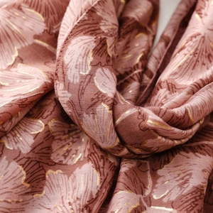 Macro detail of dusty pink scarf with gold foil floral patterns and soft fabric texture